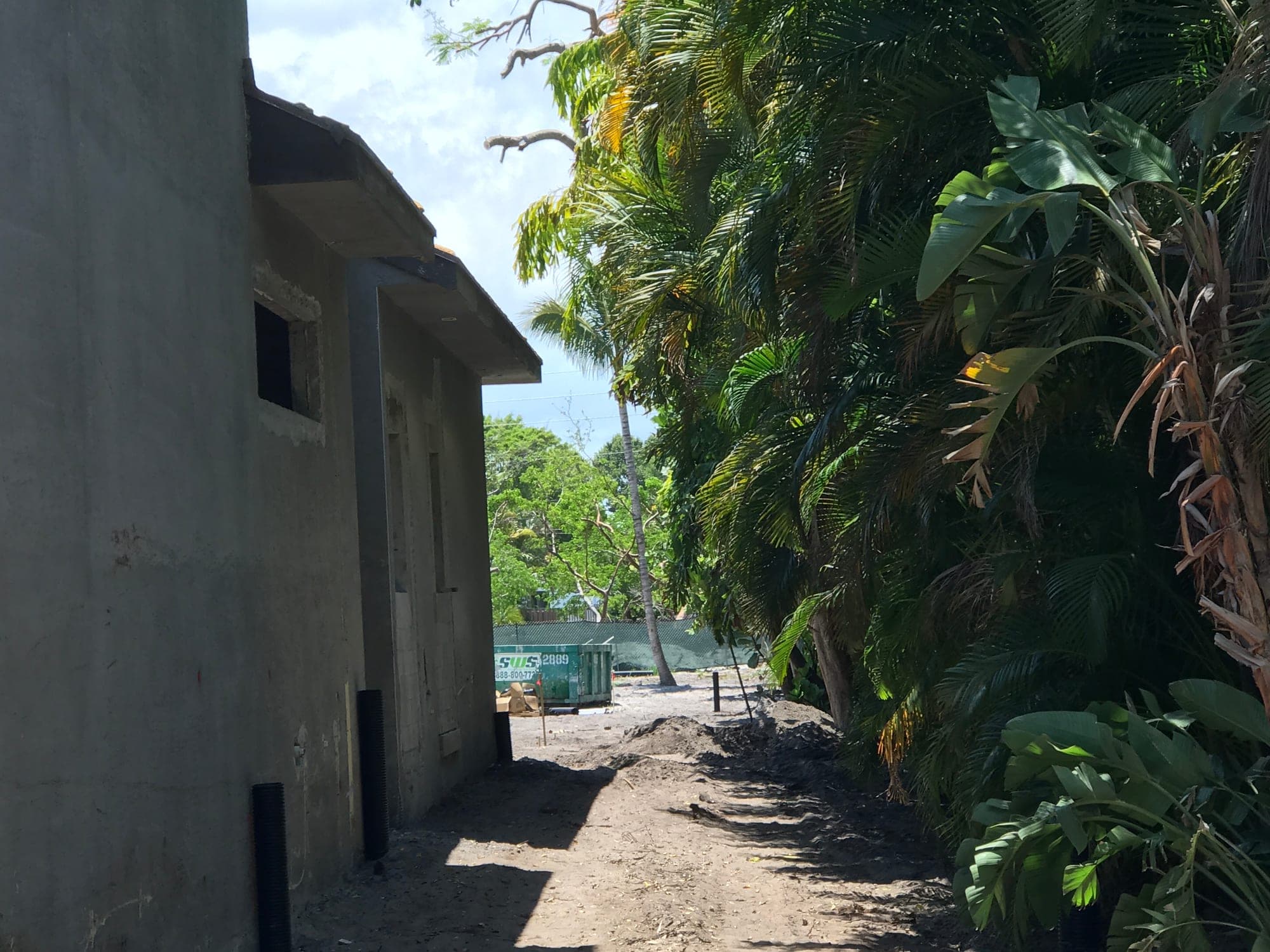 Concrete block residence under construction with palms and waterfront beyond, Palm Beach County