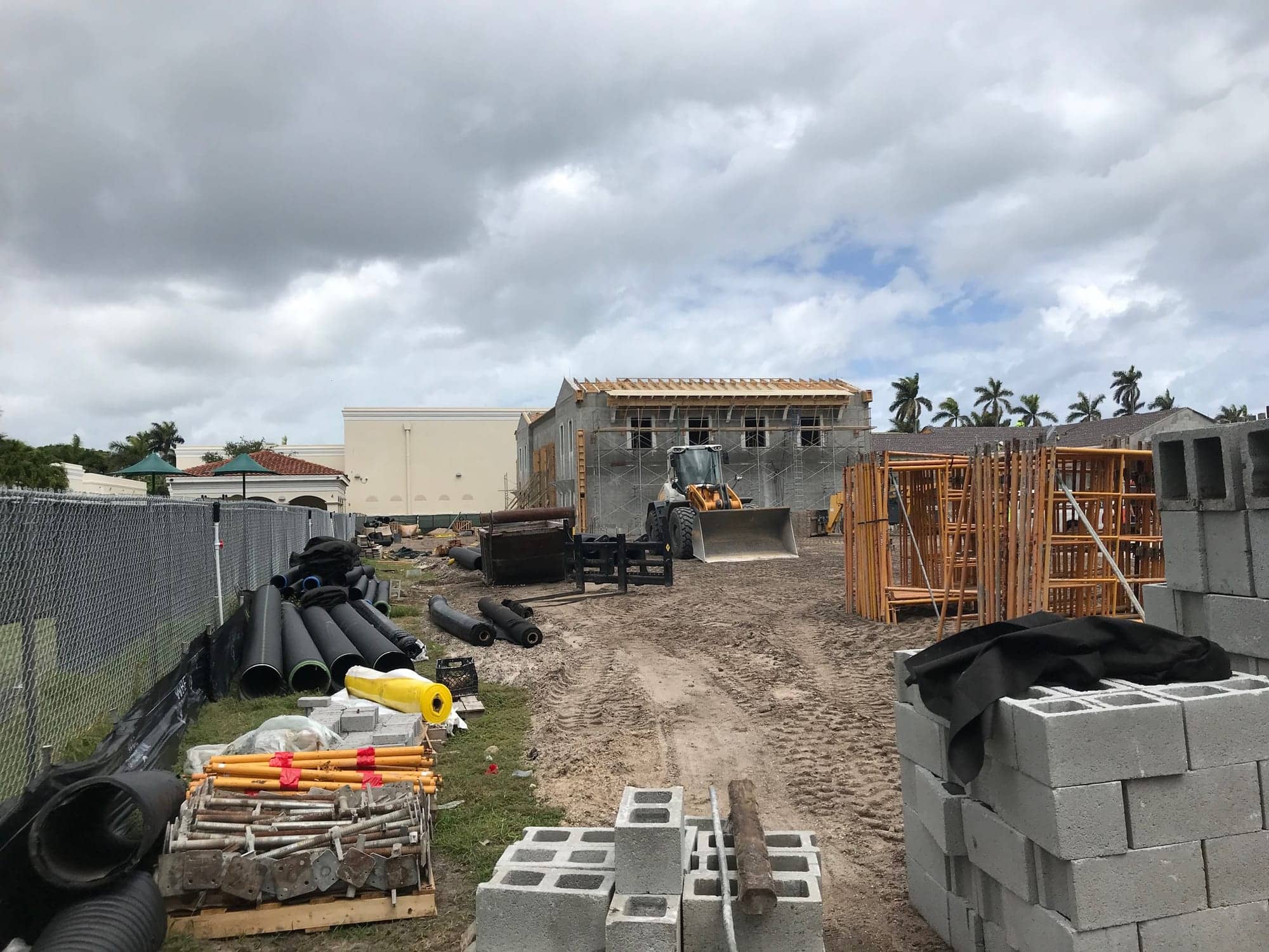 Materials staged on a commercial construction site with the building framed behind