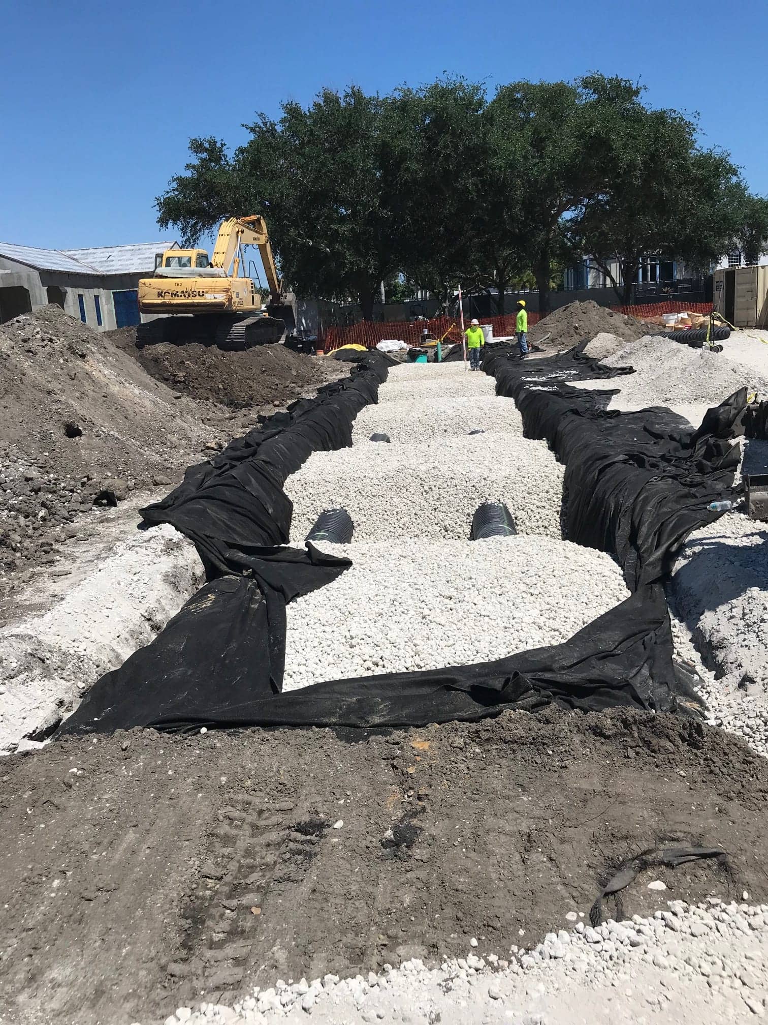 Crew installing stormwater exfiltration trenches on a construction site in Palm Beach County